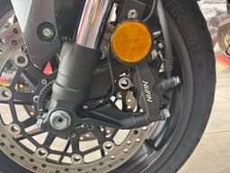 Primer plano del freno de disco delantero de una motocicleta, mostrando la pinza Nissin y el disco perforado.