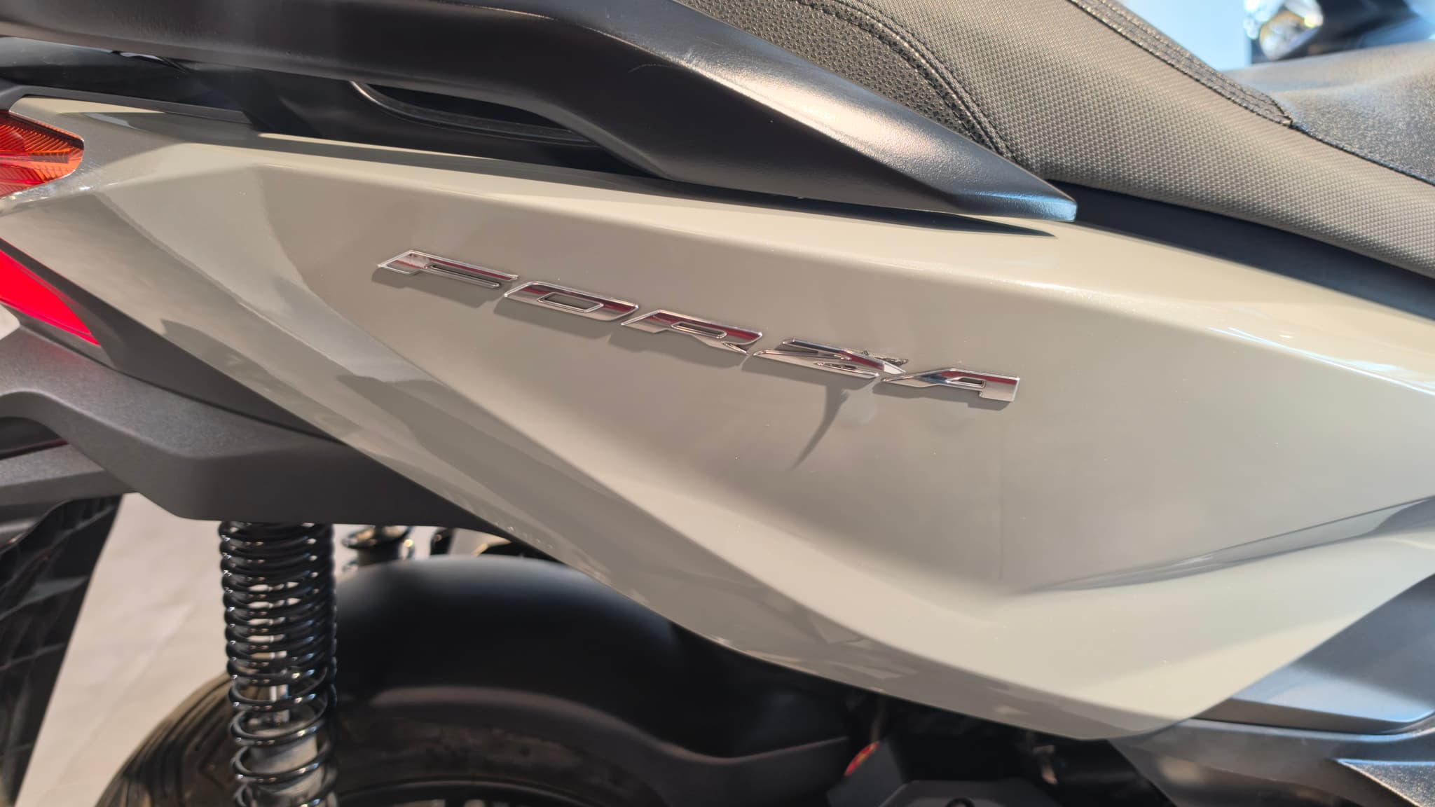 Detalle del lateral de una moto Honda Forza 125 en color blanco.