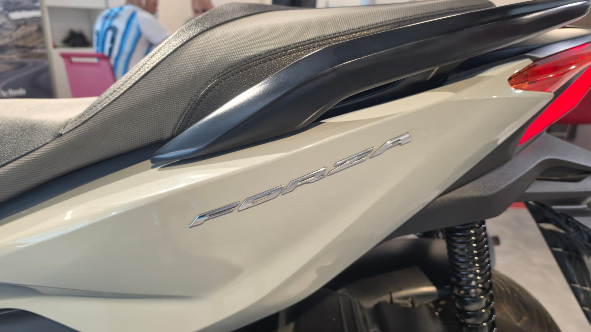 Detalle lateral de una moto Honda Forza 125 color beige