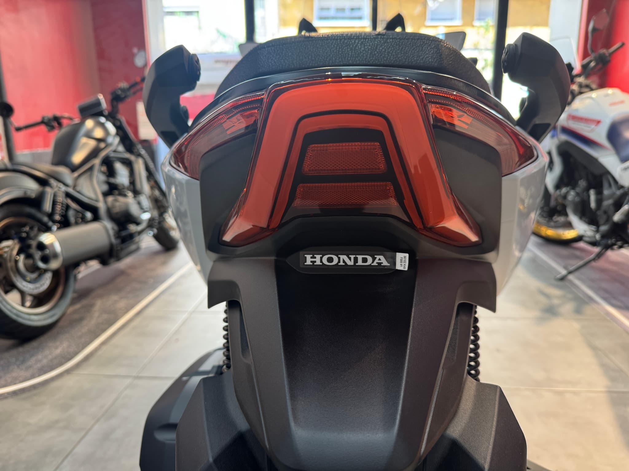 Vista trasera de la Honda Forza 125 blanca con luz de freno encendida