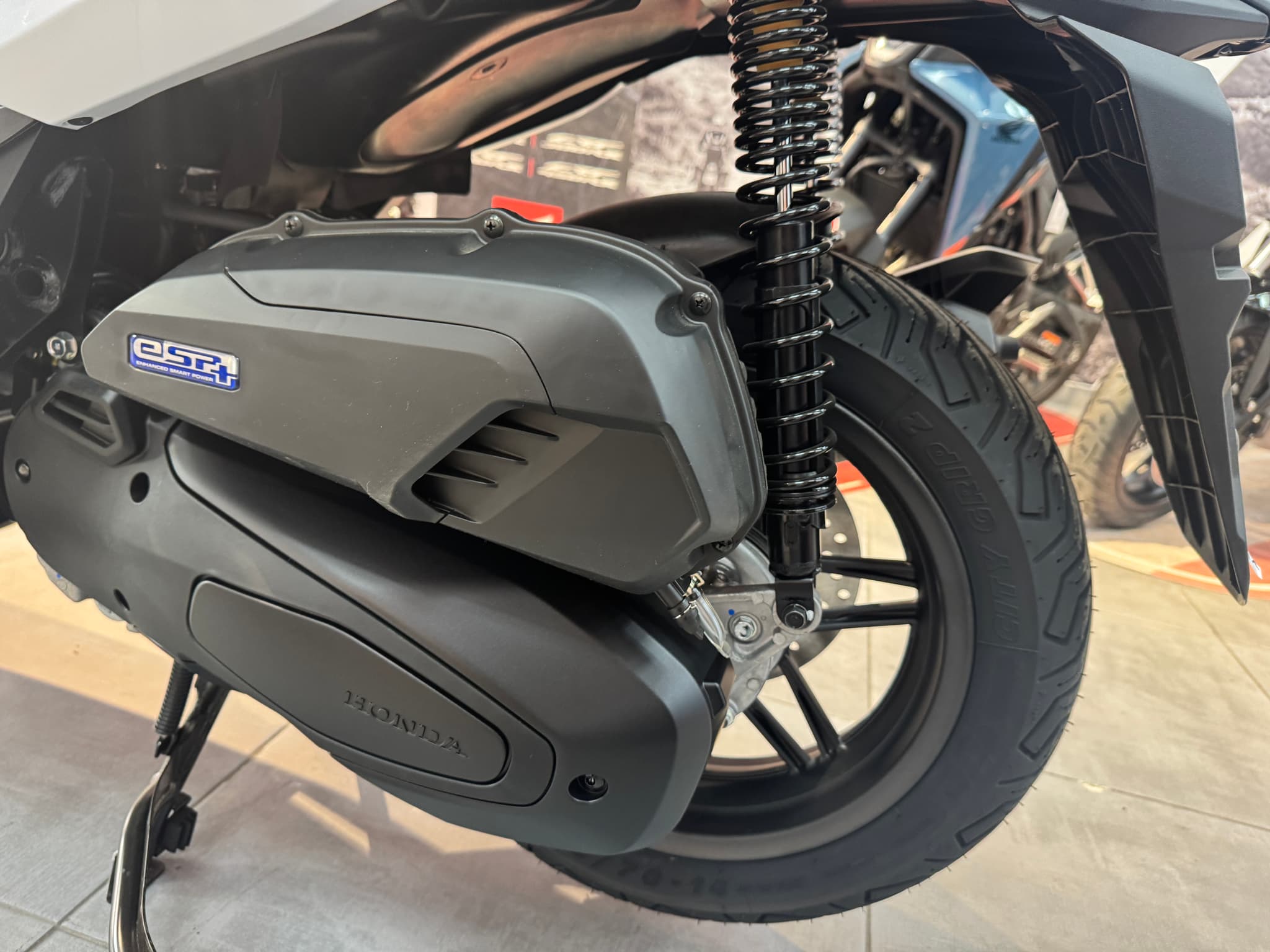Detalle de la transmisión y rueda trasera de una Honda Forza 125 blanca.