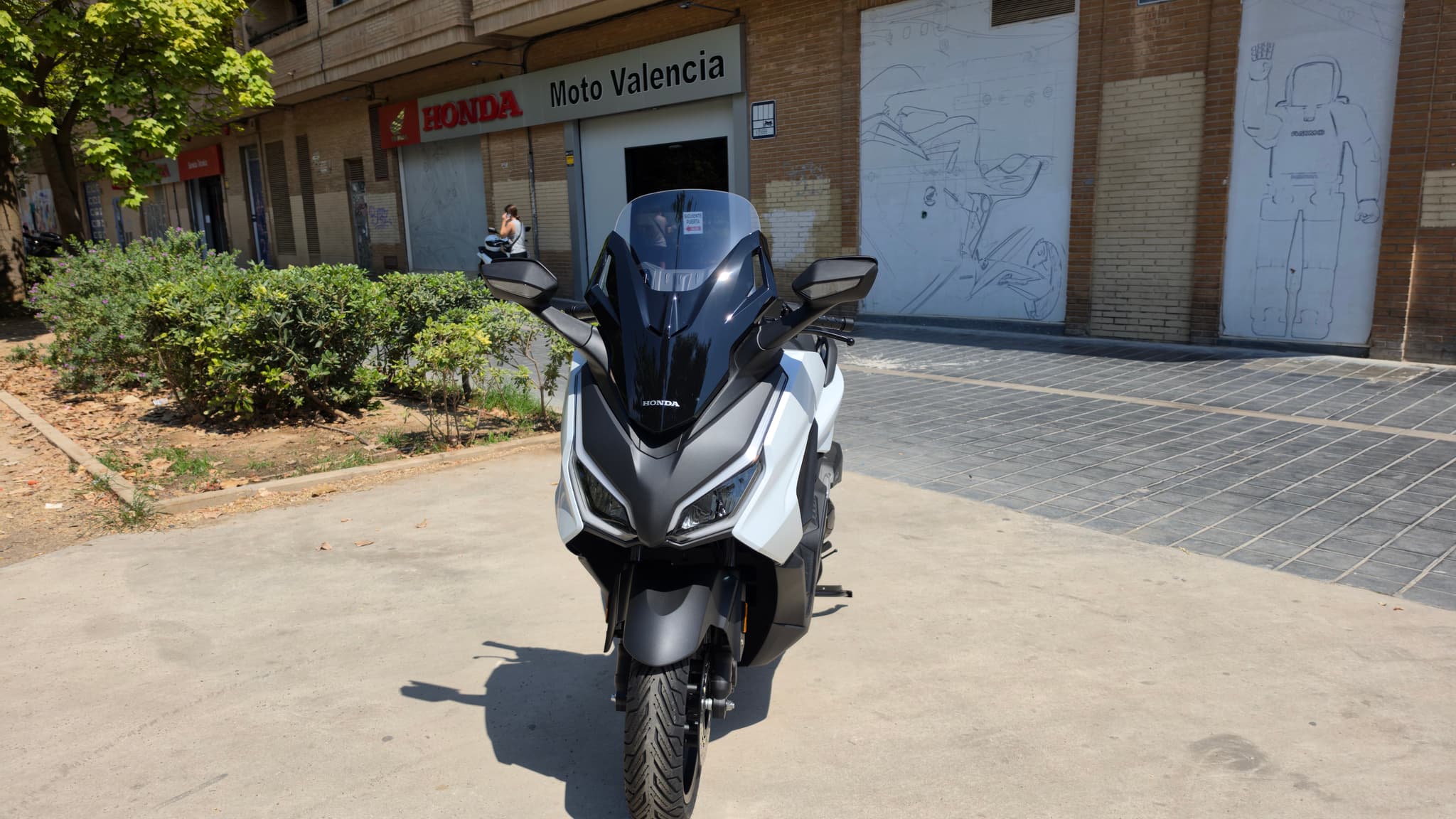 Honda Forza 125 blanca estacionada frente a concesionario Honda