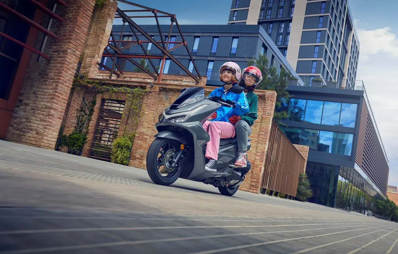 Scooter Honda PCX 125 gris con dos personas sonriendo en la ciudad