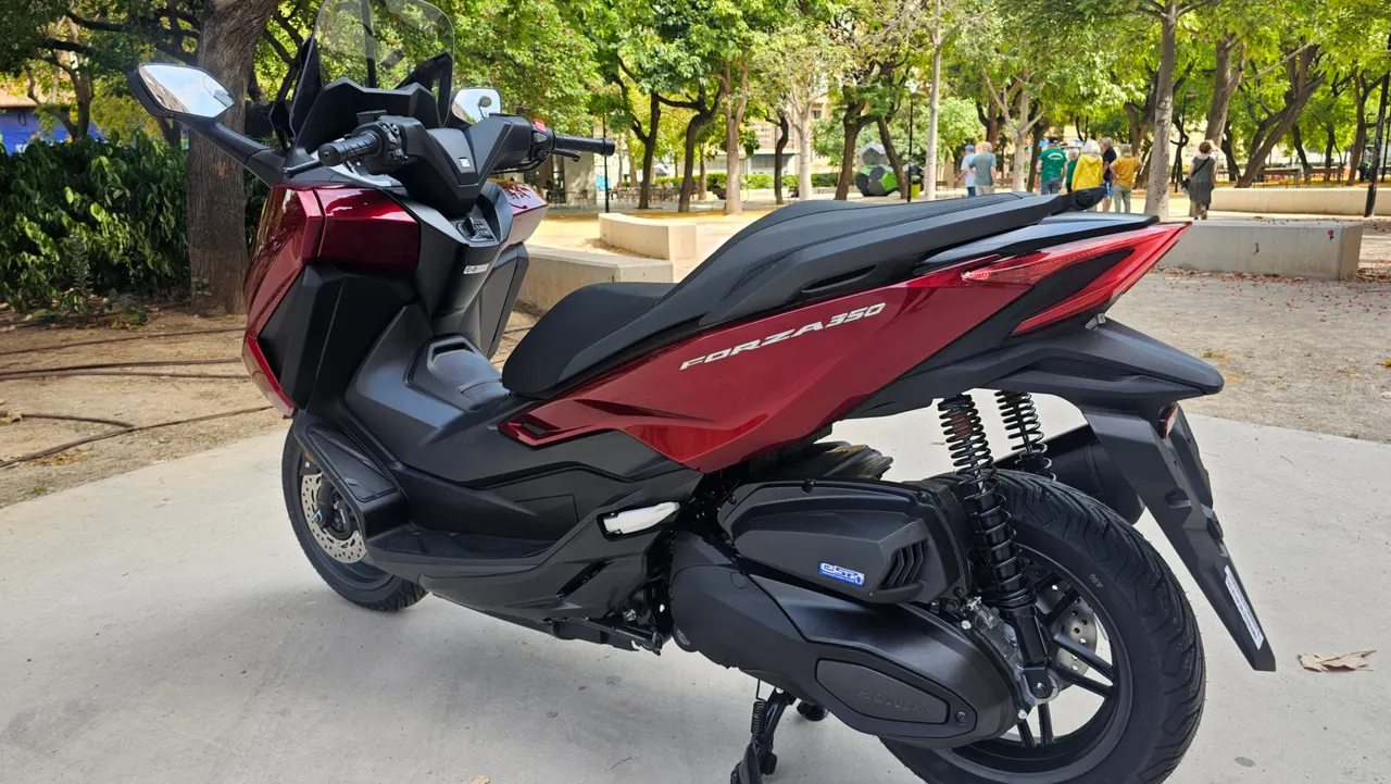 Scooter Honda Forza 350 roja estacionada en un parque
