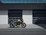 Moto Honda CB750 Hornet gris y amarilla aparcada frente a un edificio moderno