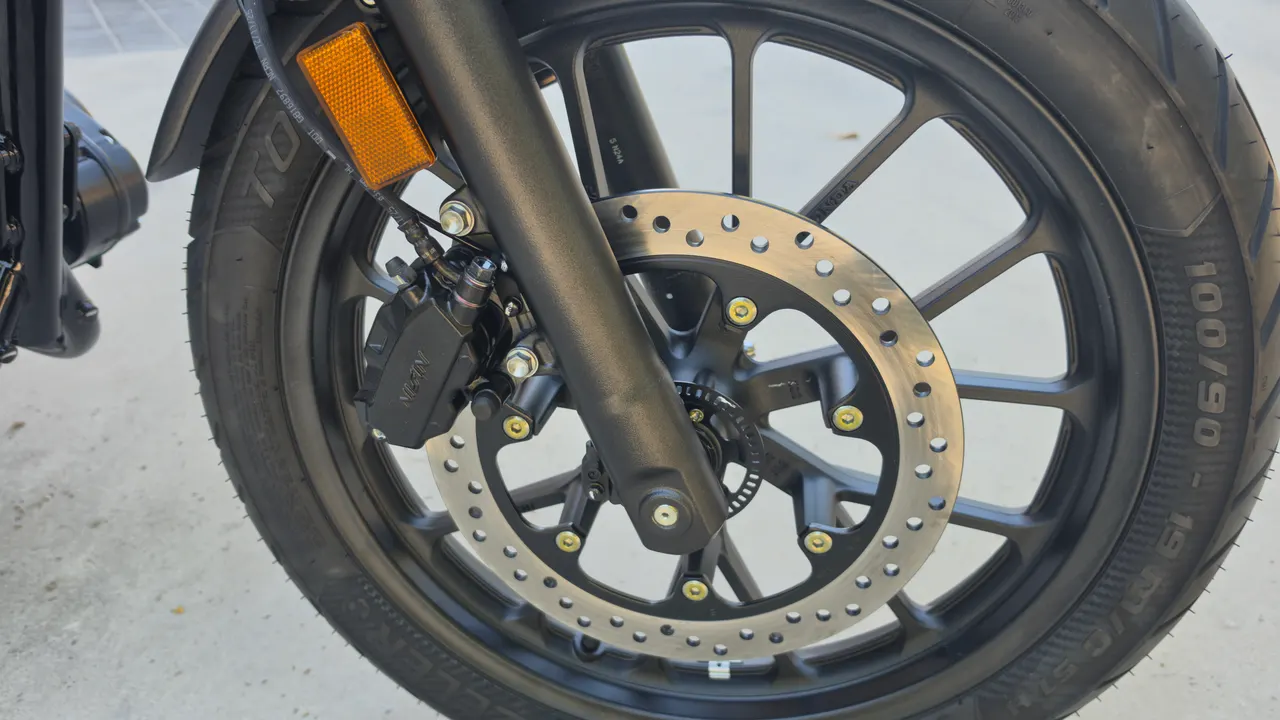 Primer plano del freno delantero de una moto Honda GB350S azul.