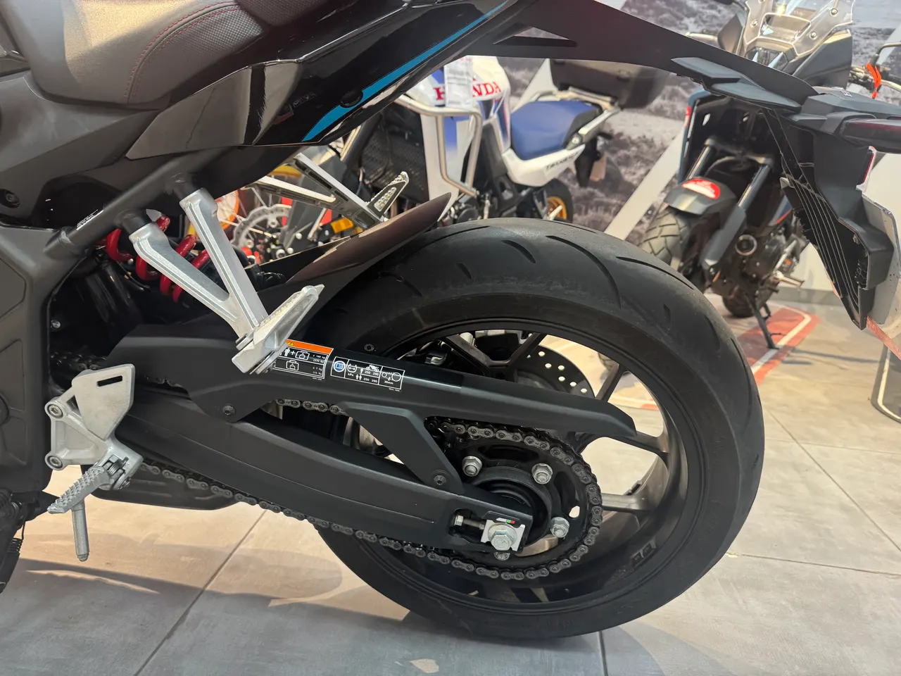 Vista detallada de la rueda trasera y basculante de una motocicleta Honda negra.