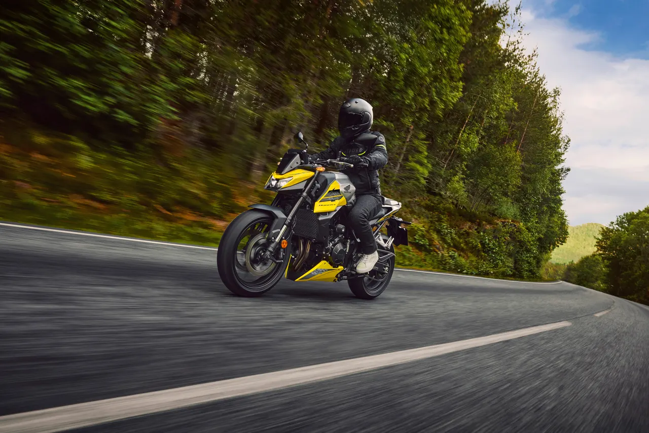Honda CB750 Hornet amarilla con piloto en carretera de montaña