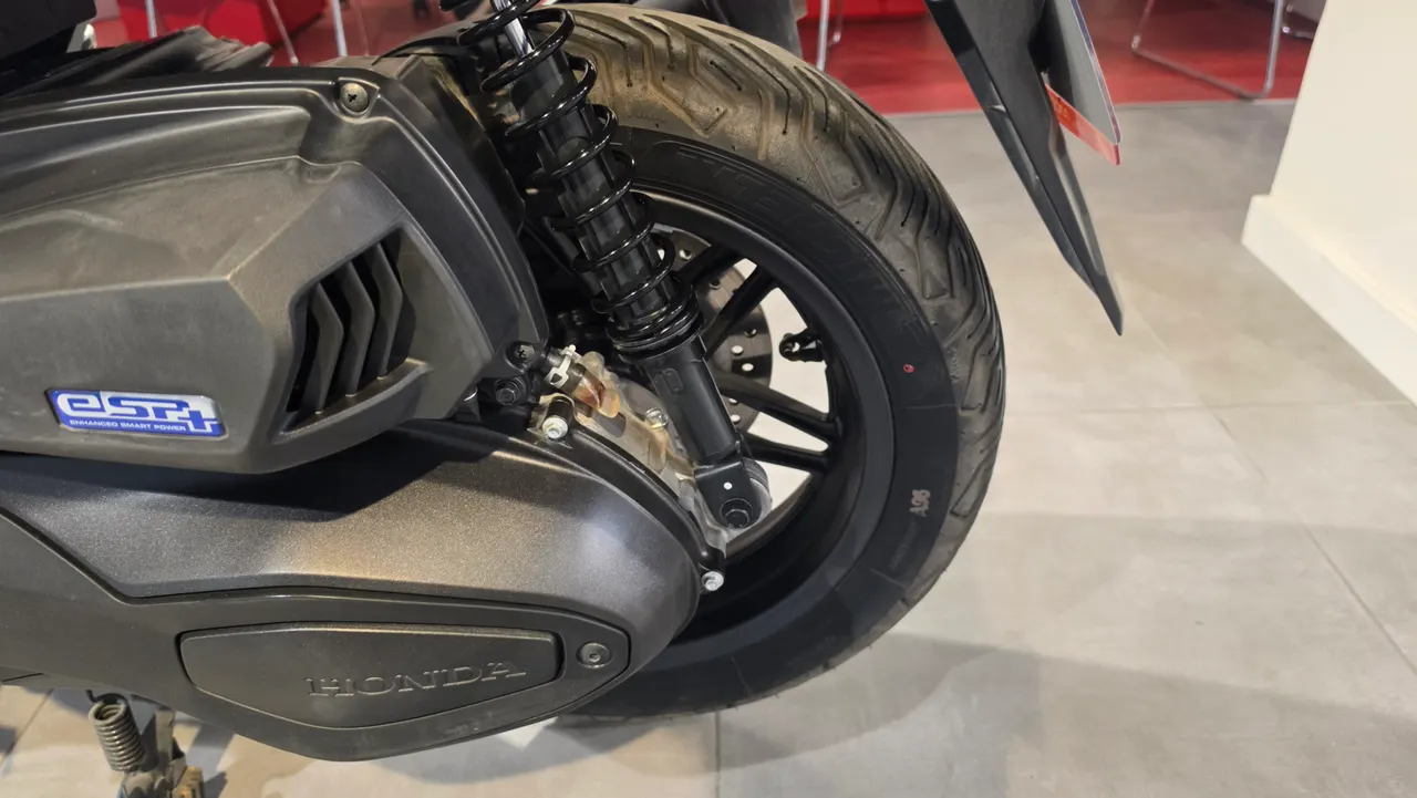 Detalle de la rueda trasera y el motor de una Honda Forza 350 en color gris oscuro.