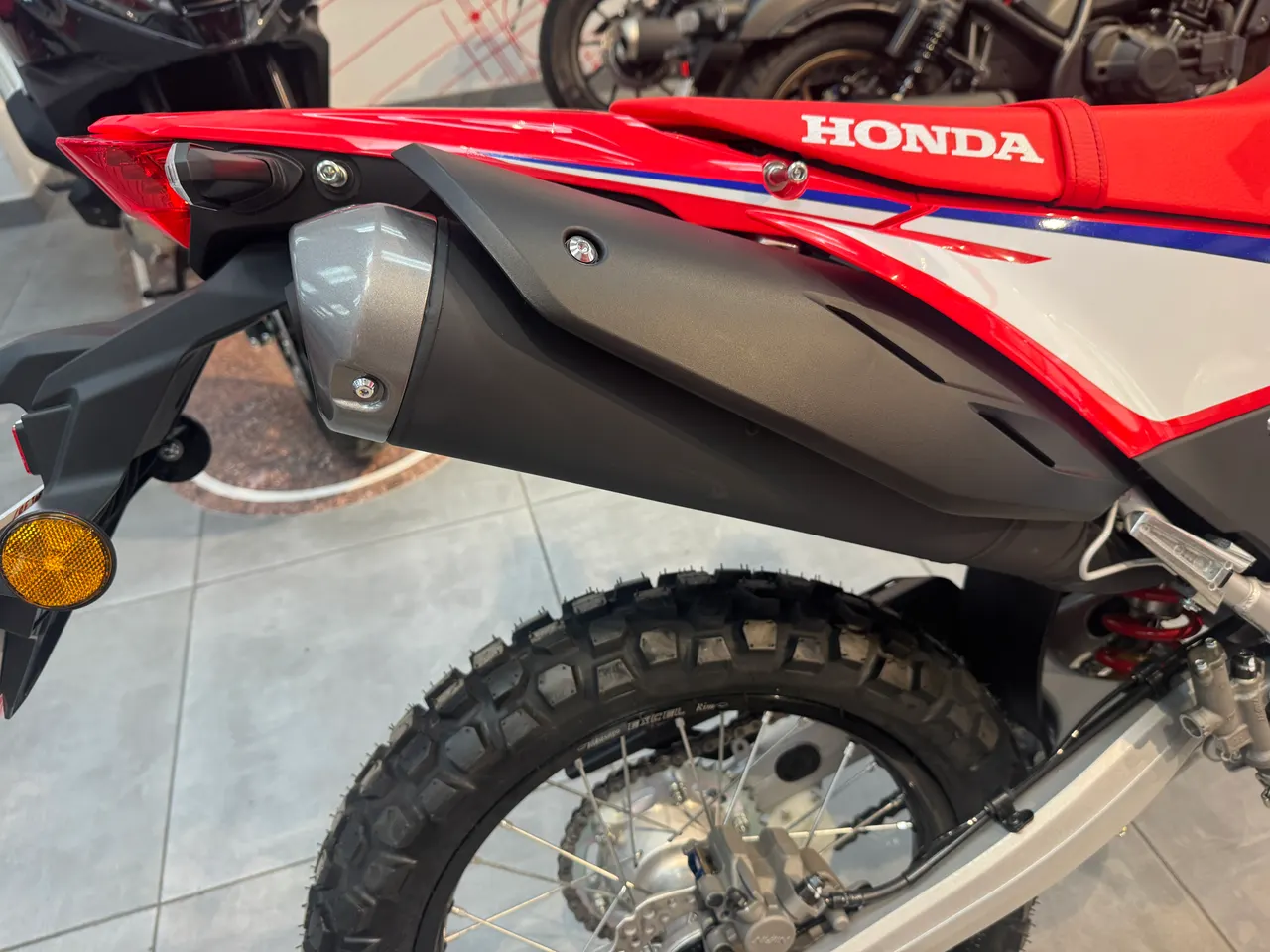 Parte trasera de la Honda CRF300L roja y blanca con escape y rueda