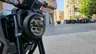 Faro delantero LED redondo de una motocicleta Honda CB125R oscura, con horquillas y radiador visibles.