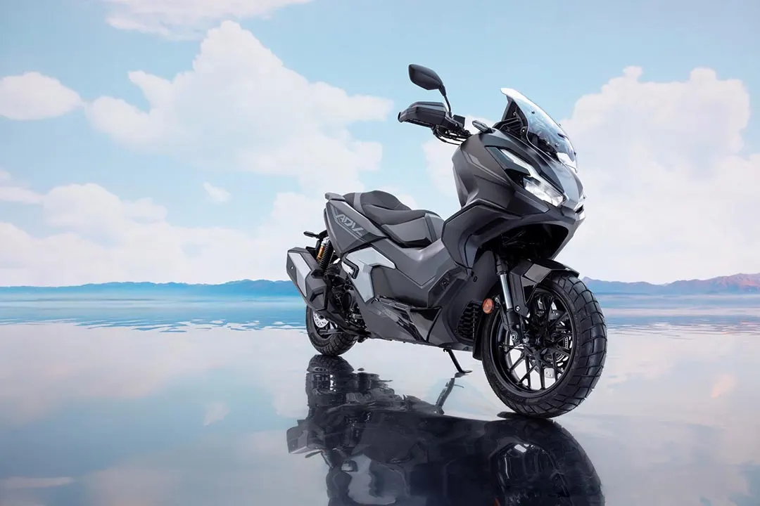 Scooter Honda ADV 350 gris oscuro en paisaje reflectante