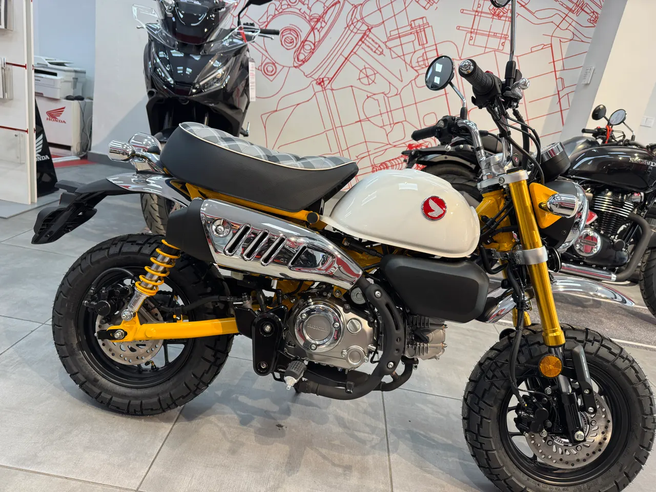 Honda Monkey amarilla con tanque blanco en exposición