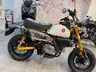 Honda Monkey amarilla con tanque blanco en exposición