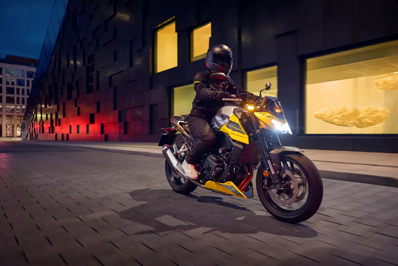 Honda CB750 Hornet amarilla circulando de noche en la ciudad.