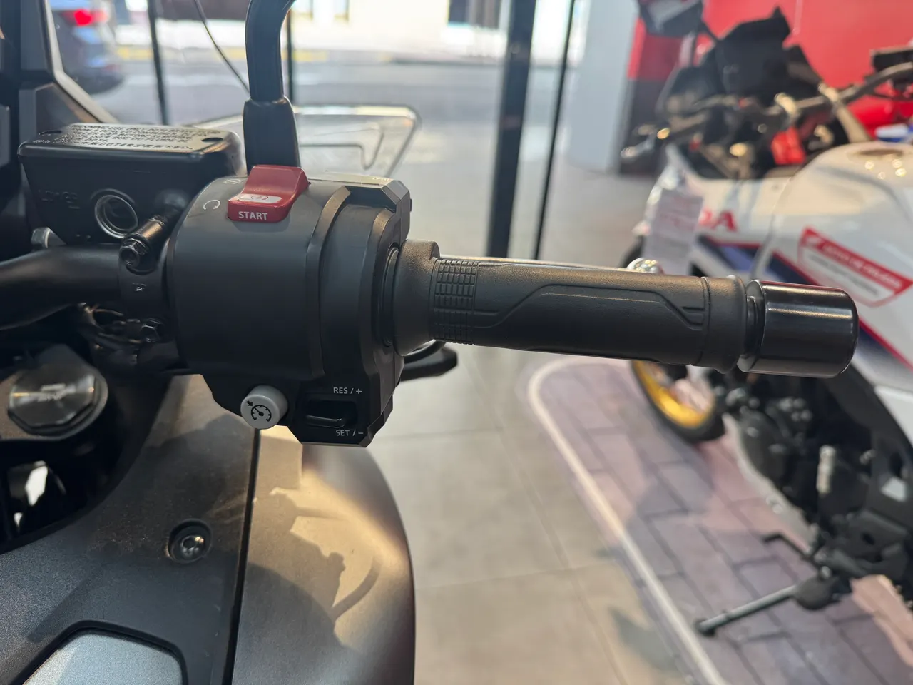 Detalle del manillar de una motocicleta con el puño de acelerador, botones de control y maneta de freno.