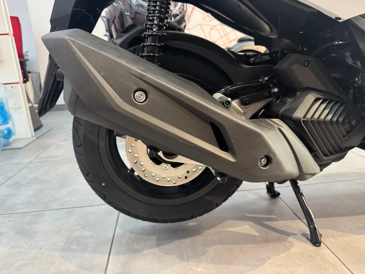 Escape, rueda trasera y freno de disco de una Honda Forza 125