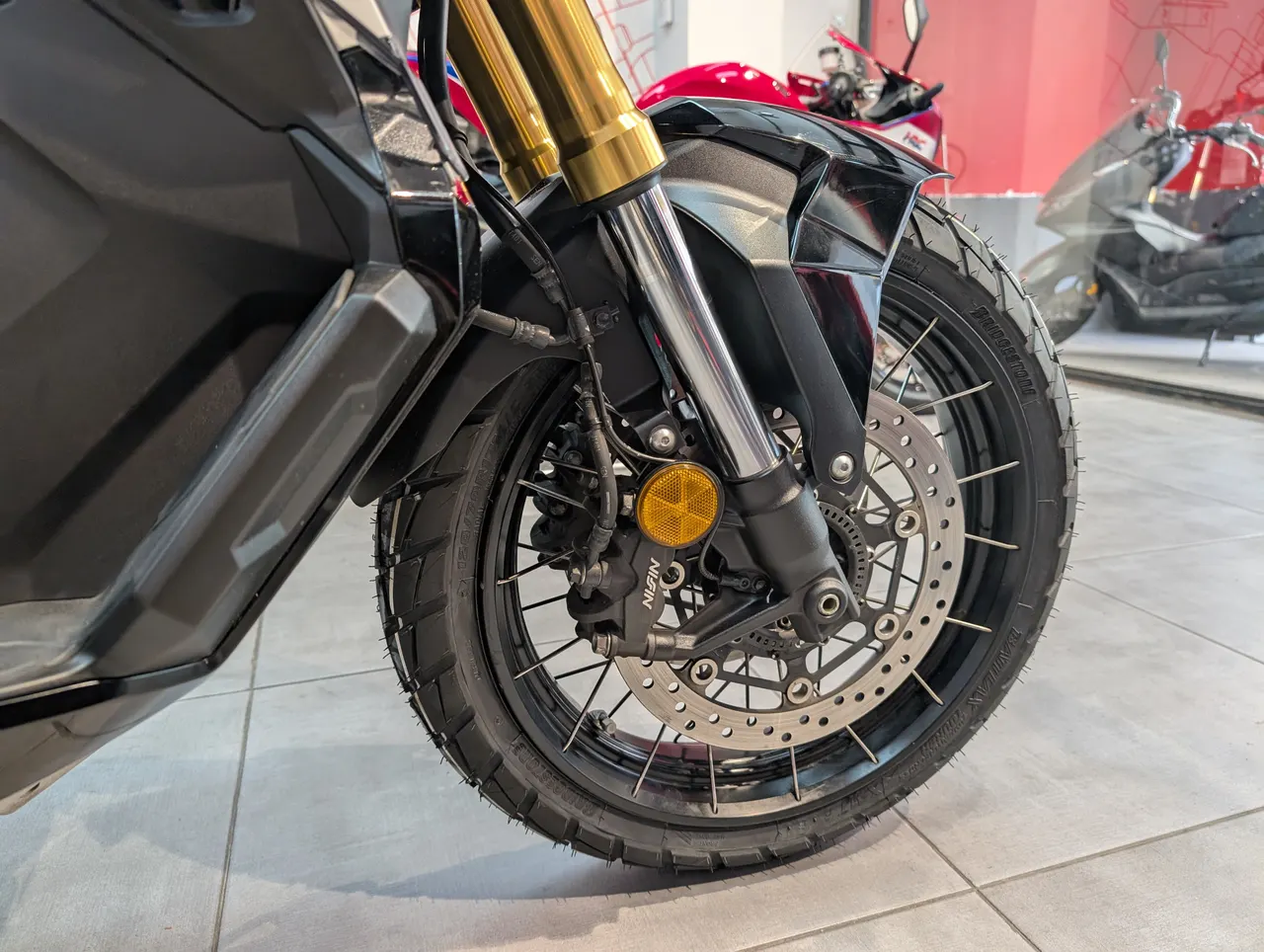 Rueda delantera de una moto Honda X-adv negra con detalles dorados en la horquilla