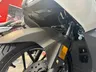 Parte delantera de una Honda Forza 125 blanca con guardabarros oscuro y señal naranja