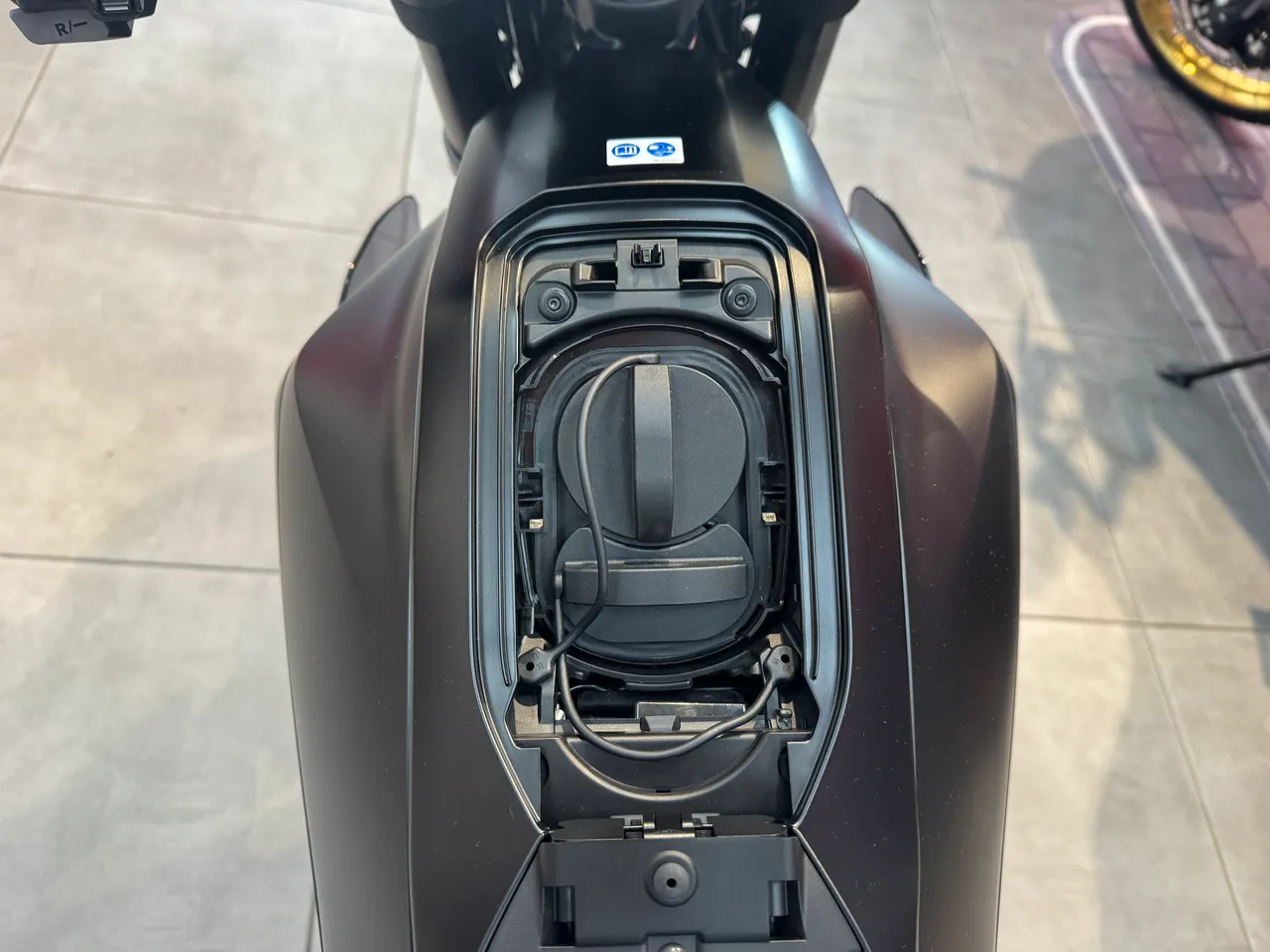 Compartimento de asiento abierto de una moto Honda WN7 negra graphite