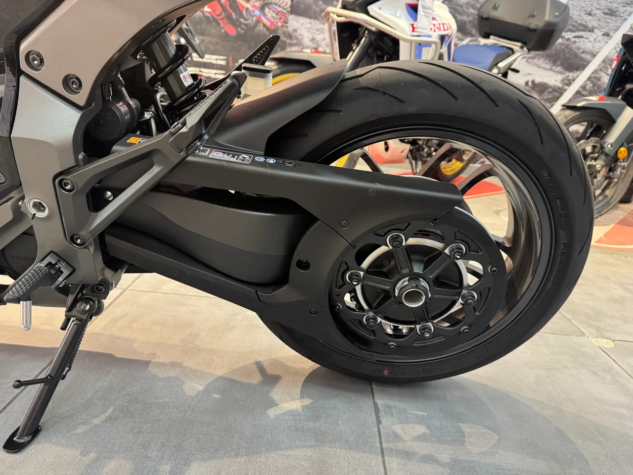 Detalle de la rueda trasera y basculante de una moto Honda WN7 negra graphite.