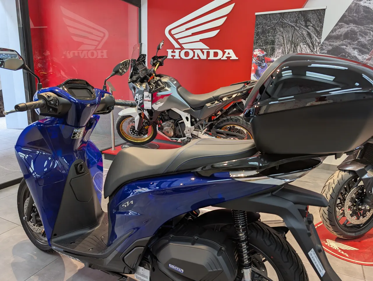 Honda SH125i scooter azul con top case en concesionario