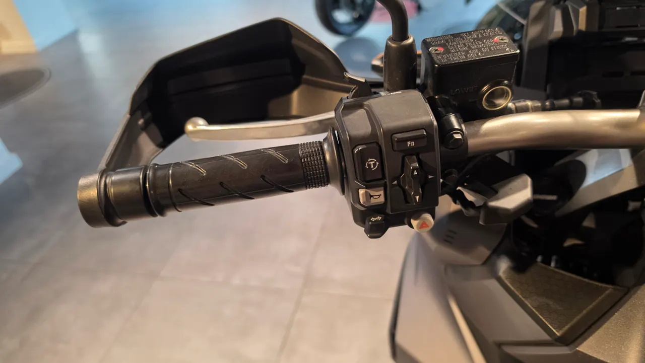 Detalle del manillar de una motocicleta con puño, freno y controles de navegación.