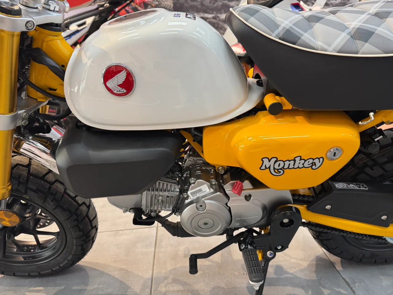 Moto Honda Monkey amarilla con tanque blanco y asiento a cuadros