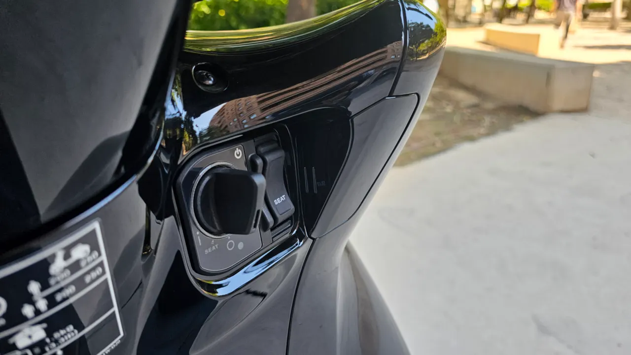 Cerradura de encendido y botón de apertura del asiento de una moto Honda SH350i negra.