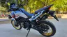 Honda CRF1100L Africa Twin blanca con detalles azules y rojos, ruedas doradas, vista trasera.