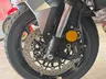 Primer plano de la rueda delantera de una motocicleta, mostrando el disco de freno, la pinza Nissin y la horquilla delantera.