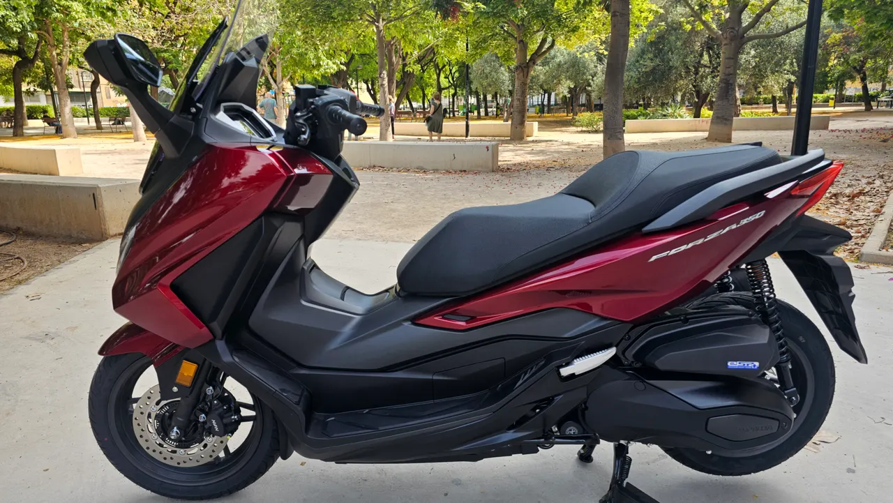 Scooter Honda Forza 350 rojo carnelian mate en un parque