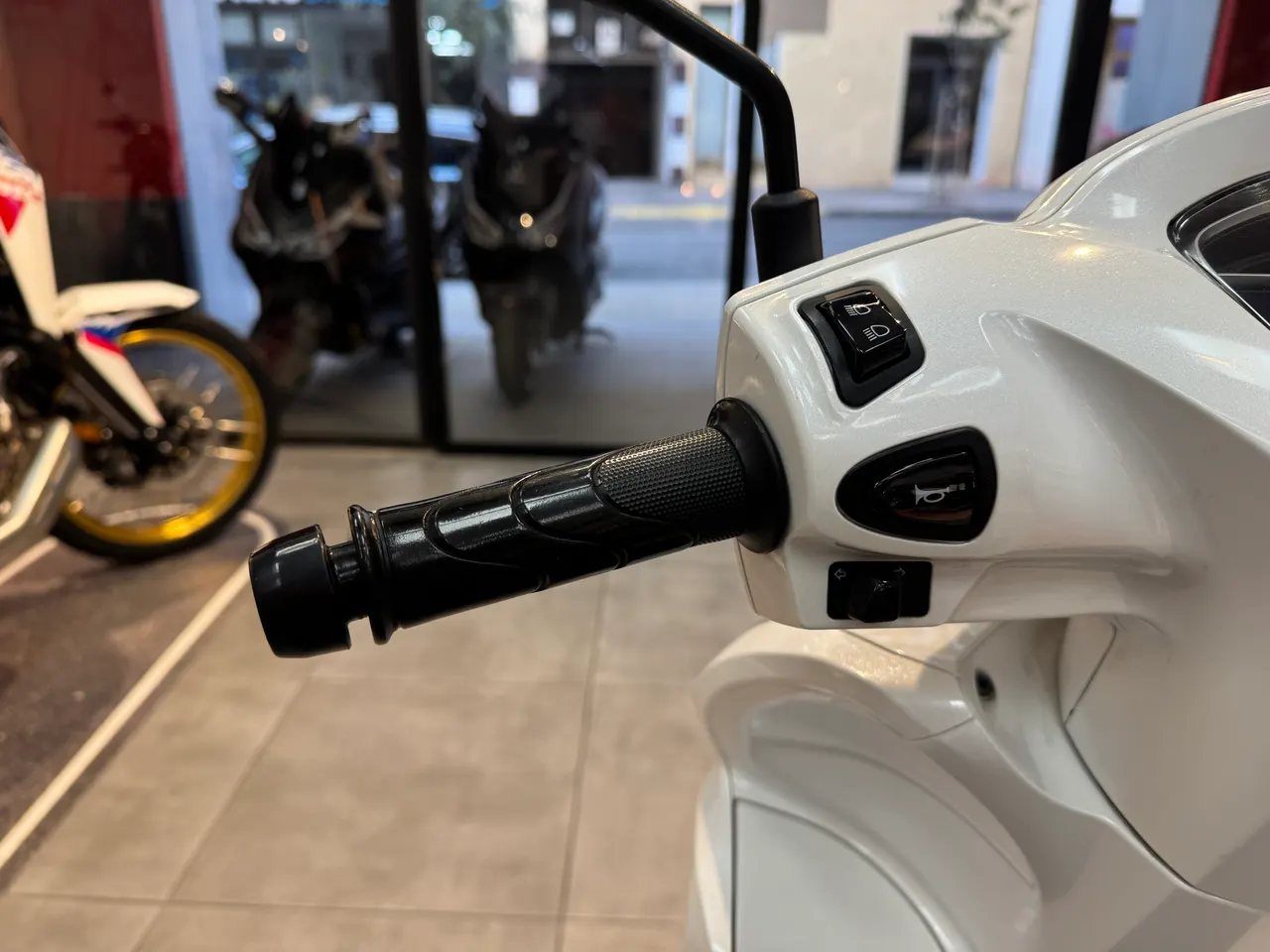 Detalle del manillar de una moto Honda Vision blanca