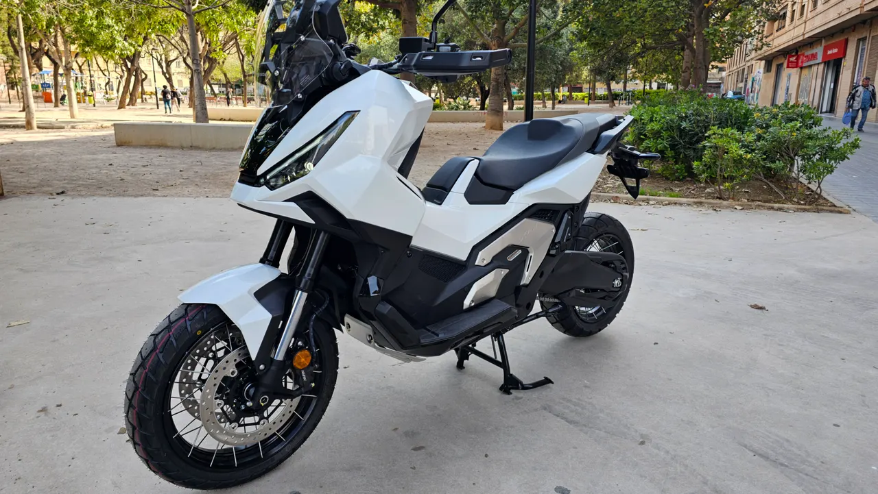 Honda X-ADV blanca aparcada en una acera urbana