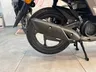 Detalle de la rueda trasera y escape de Honda Vision 110 marrón mate