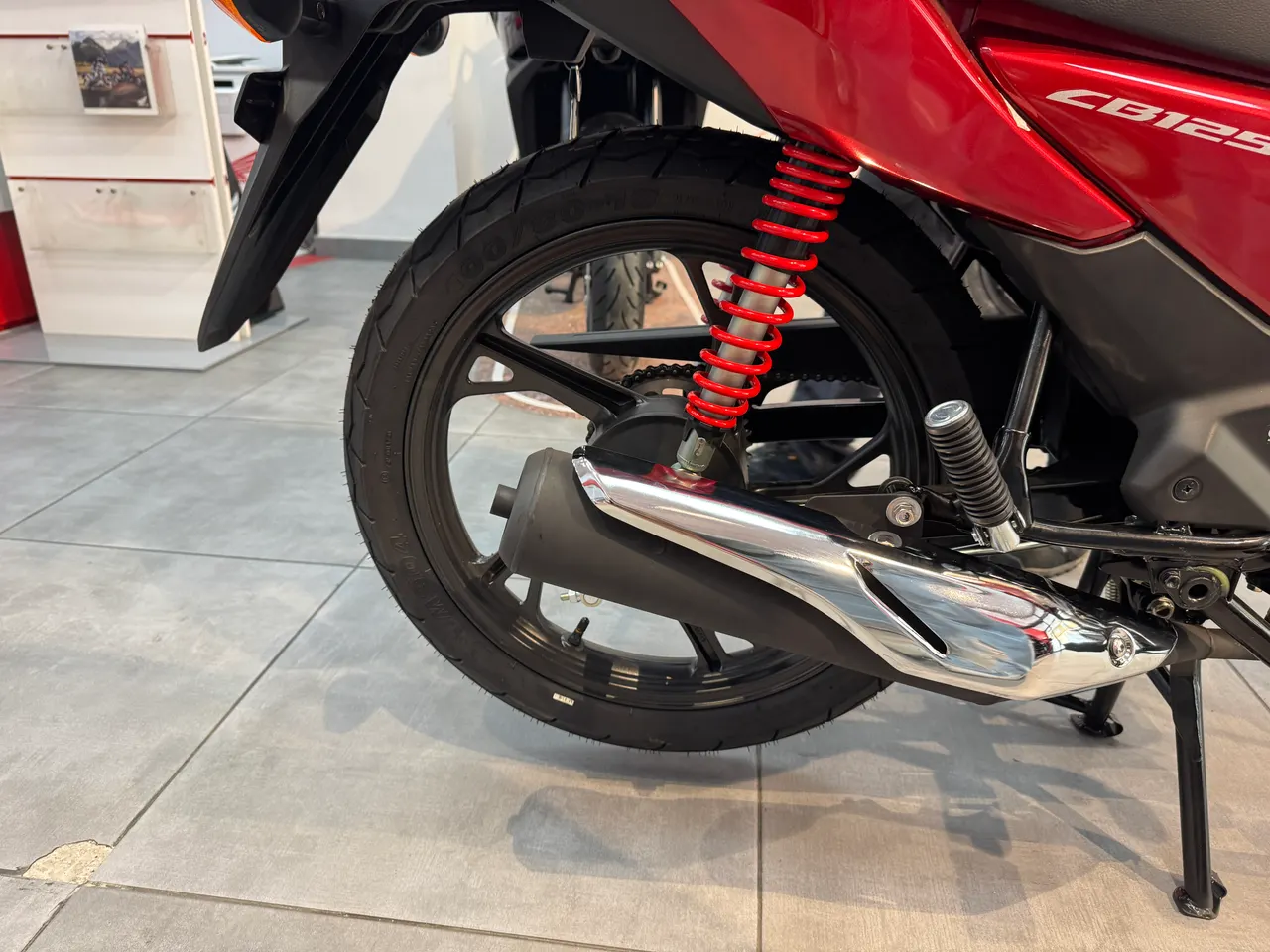 Detalle del escape, llanta trasera y amortiguador de una Honda CB125F roja R-355.