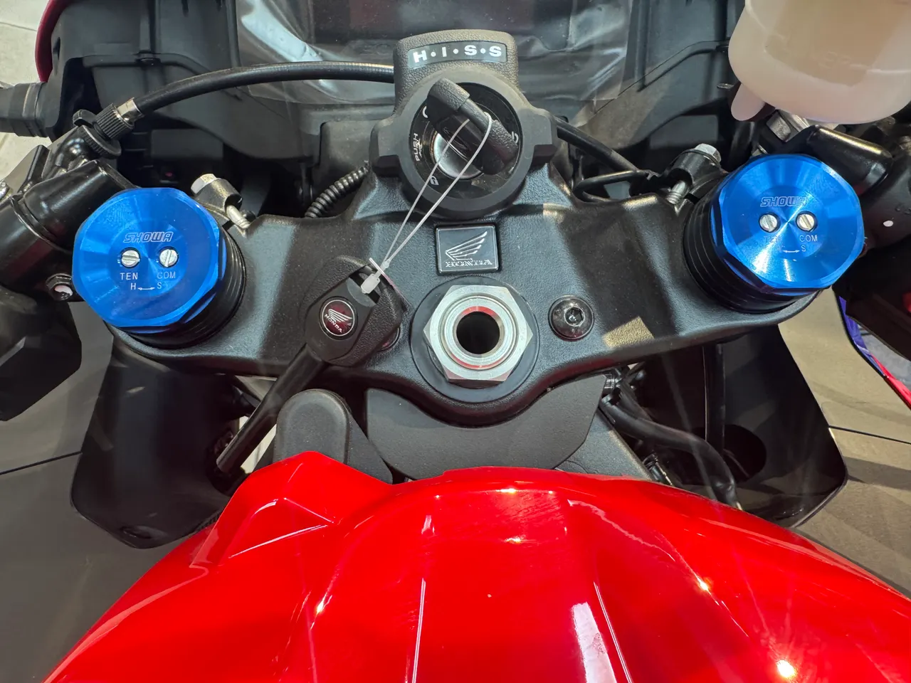 Detalle del manillar de una Honda CBR 600RR roja con tapas de suspensión azules.