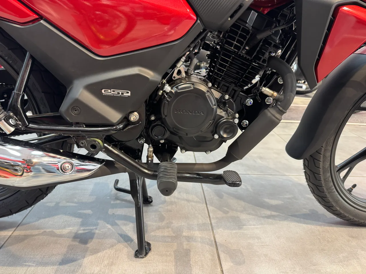 Detalle del motor y partes inferiores de una moto Honda CB125F de color rojo.
