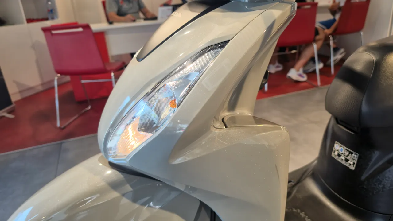 Detalle frontal de scooter Honda Vision 110 color beige en un concesionario