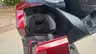 Compartimento de almacenamiento delantero abierto de una Honda Forza 350 roja con puerto USB