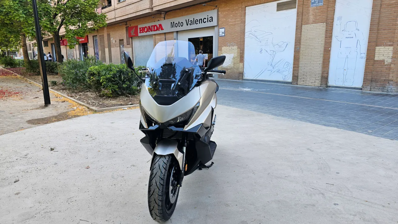 Honda Forza 750 gris mate estacionada frente a concesionario