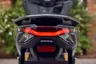 Vista trasera de la scooter Honda PCX 125 gris oscuro con luz trasera LED encendida