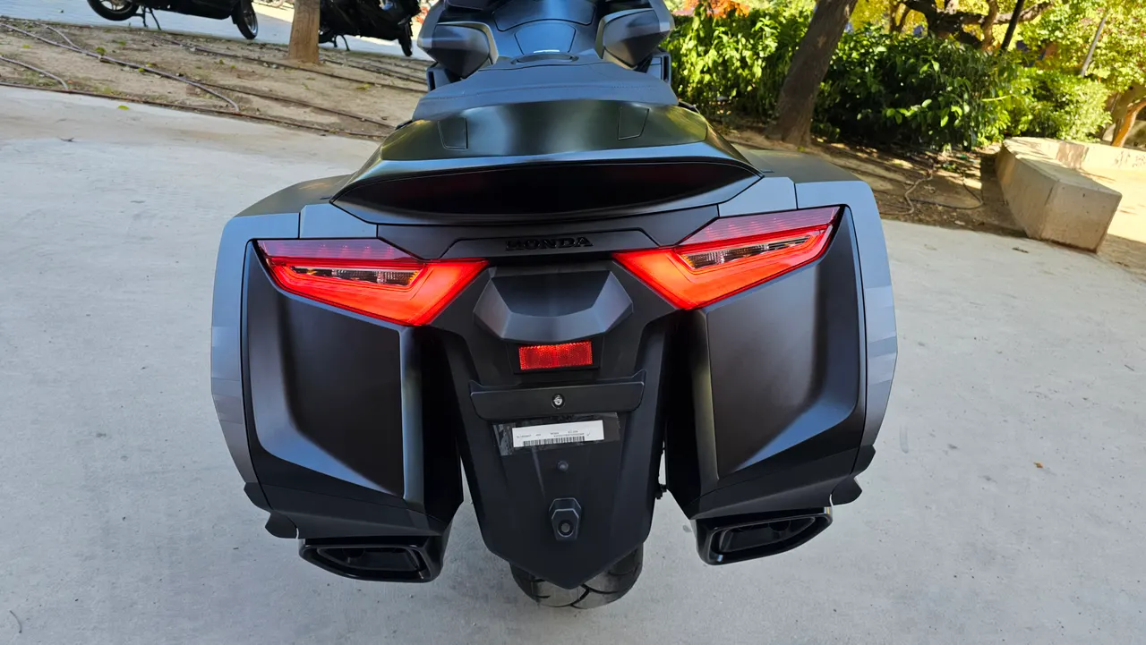 Vista trasera de la Honda Gold Wing DCT negra mate con luces LED encendidas y maletas laterales.