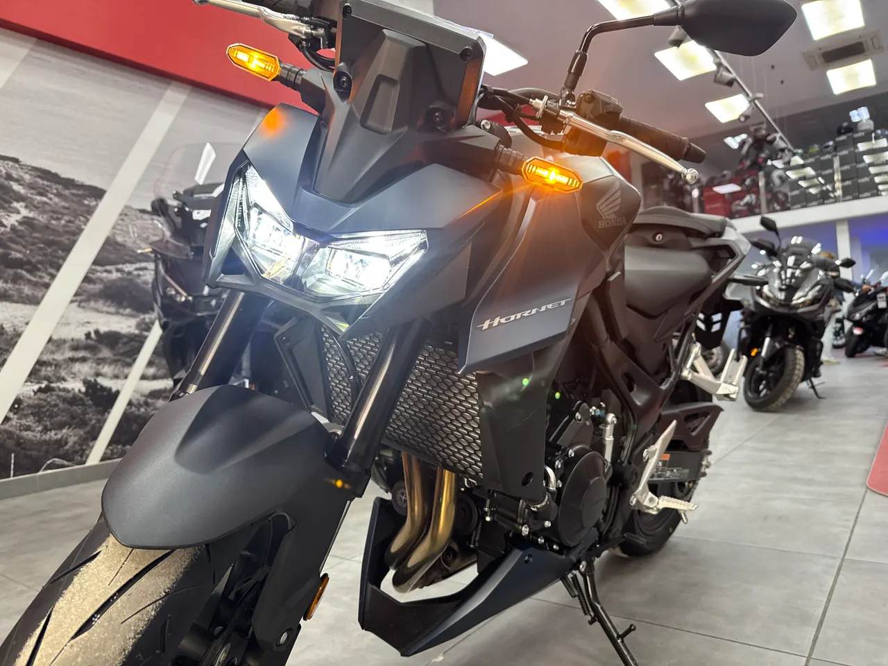 Honda CB750 Hornet gris oscuro con luces encendidas en un concesionario