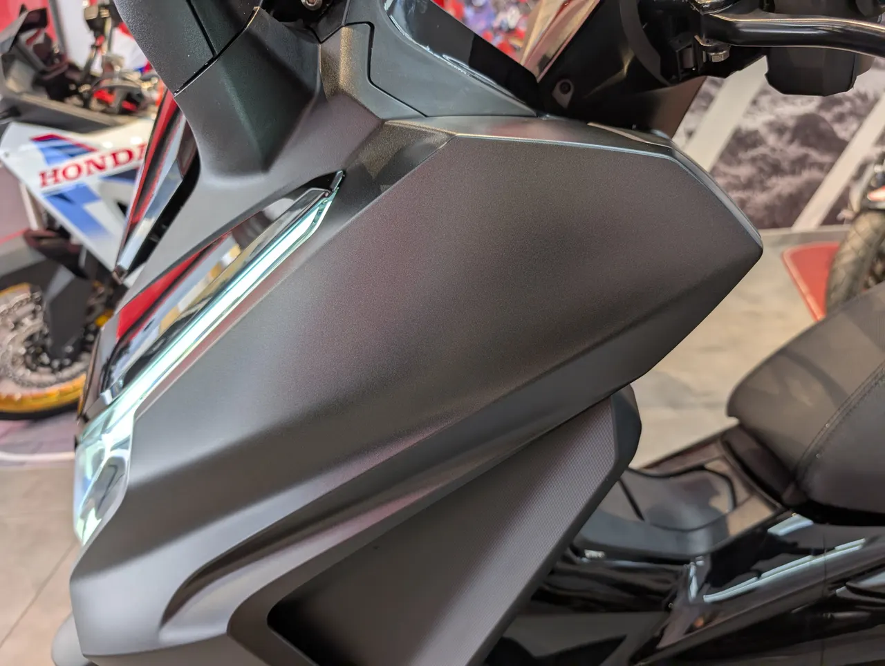Detalle frontal de scooter gris mate con luz LED