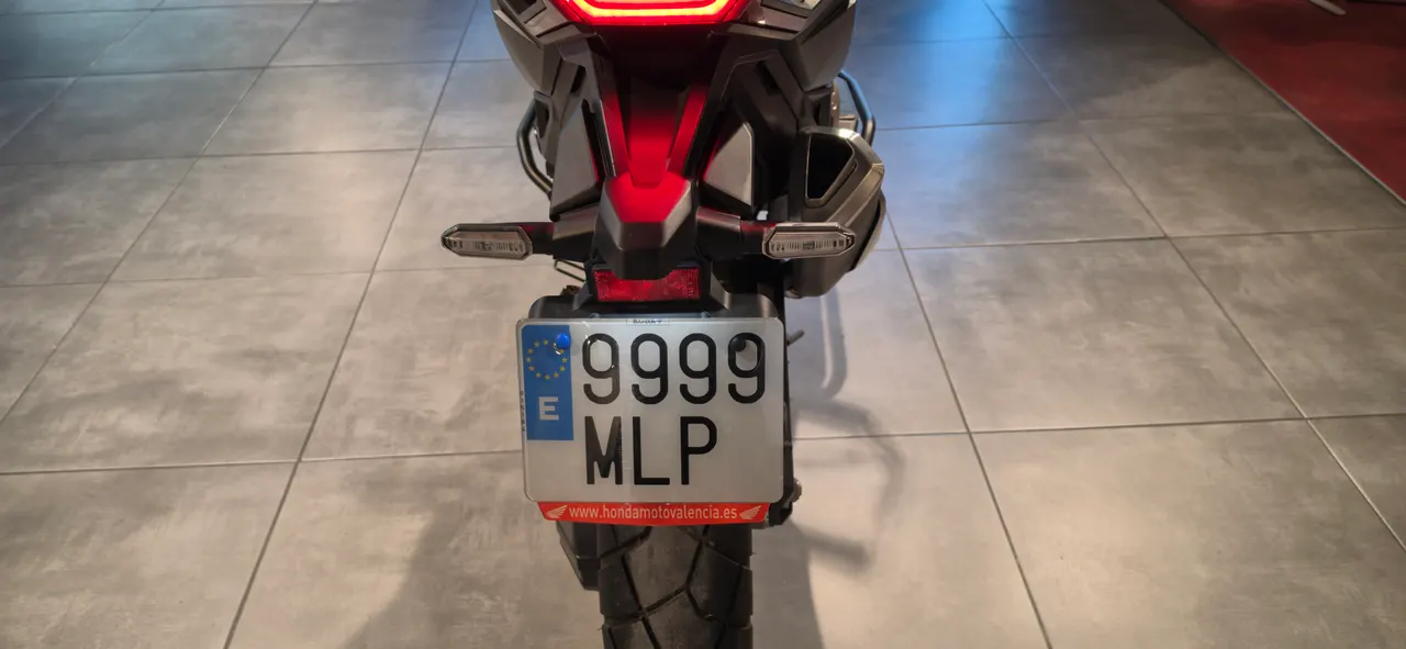 Vista trasera de una motocicleta con matrícula española y luces LED encendidas.