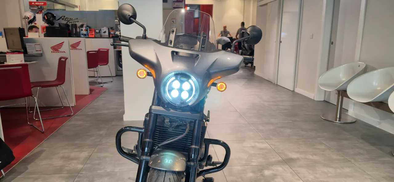 Vista frontal de una Honda Rebel 1100 gris con el faro encendido