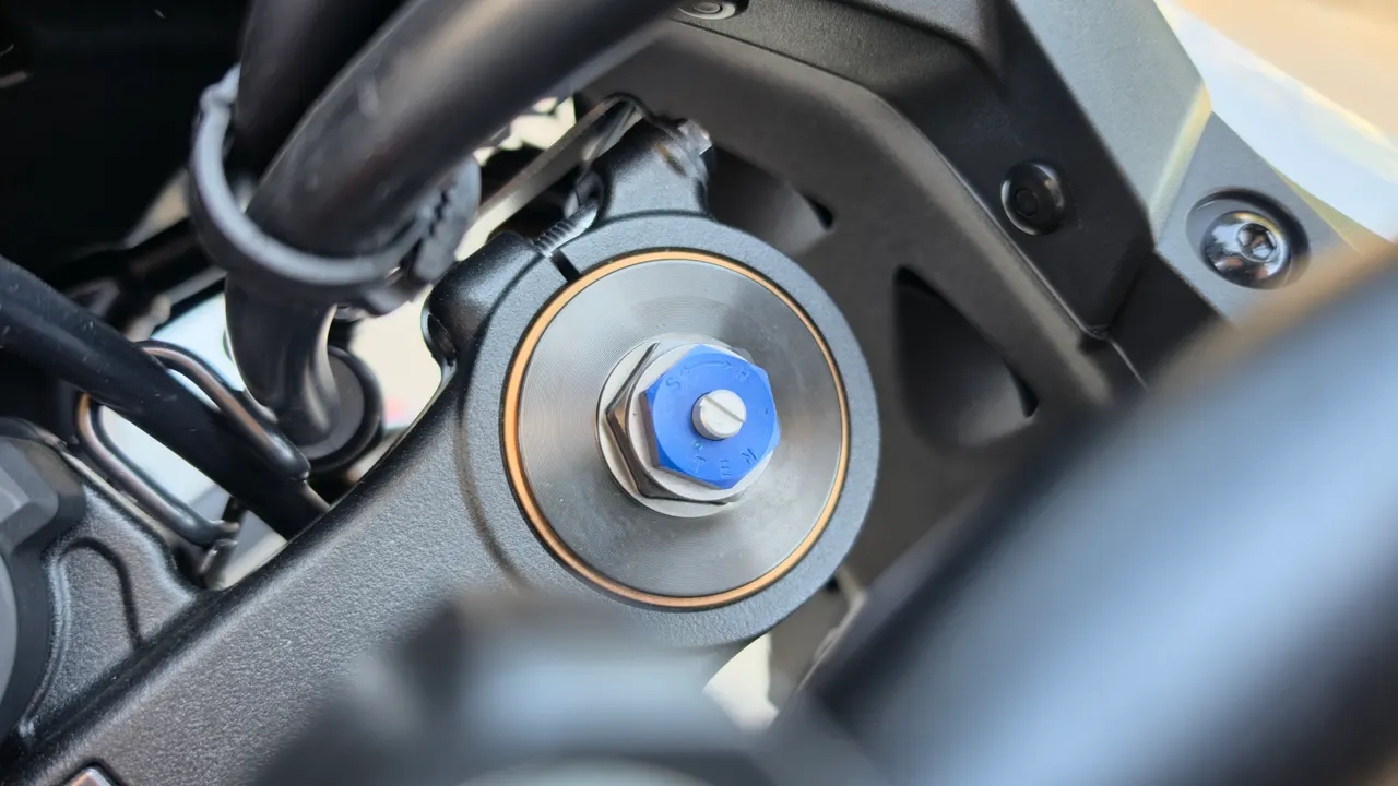 Primer plano de la parte superior de la horquilla delantera de una Honda Africa Twin con tuerca azul.