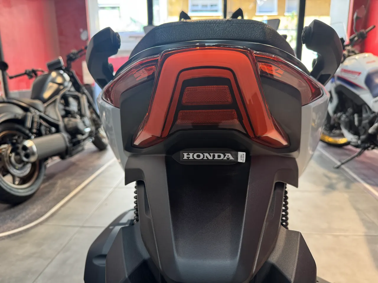 Vista trasera de la Honda Forza 125 blanca con luz de freno encendida