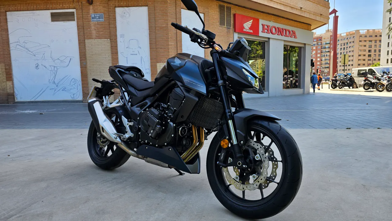 Moto Honda CB750 Hornet negra aparcada frente a un concesionario Honda.